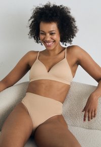 Beige bikini set featuring a triangle bralette with adjustable straps and high-waisted bottoms, made of soft, smooth fabric.