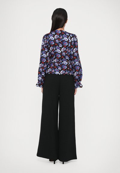 Top a maniche lunghe floreale in blu navy, caratterizzato da vivaci motivi floreali, abbinato a pantaloni neri a gamba larga realizzati in tessuto testurizzato.