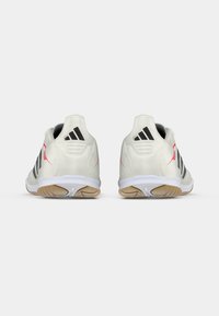 Ζευγάρι λευκών αθλητικών παπουτσιών Adidas με μαύρες ρίγες και κόκκινες λεπτομέρειες, εικονογραφημένα από πίσω σε λευκό απλό φόντο.