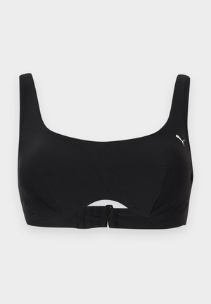 Fekete sports melltartó széles pántokkal, kerek nyakkivágással, elülső kapoccsal és kis fehér Puma logóval a bal oldalon.