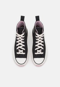 Svarta högskor med texturerad ovandel, rosa innersula, vita snören och gummisula med vit tåhuvud.