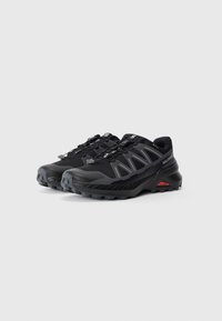 Pair of black Salomon trail running shoes with gray accents, rugged soles, and quick-lace system, set on white background.