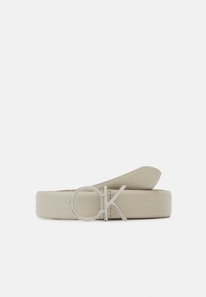 Cintura in pelle grigia chiara con una texture liscia, dotata di una fibbia circolare argentata con le lettere "CK" e una estremità affusolata per la regolazione.