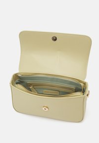 Ljusgrön rektangulär handväska med en slät yta. Har guldfärgad hårdvara, ett dragkedjefack inuti och flera fack.