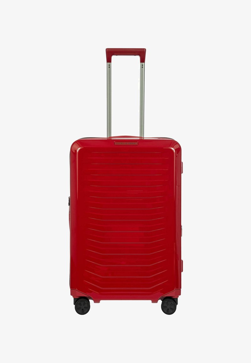 Sicuro con trama ondulata, valigia rigida rossa con scanalature verticali, manico estensibile e quattro ruote nere per la mobilità. Texture liscia e zipper sicura.