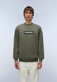 Olijfgroen sweatshirt met een ronde hals, lange mouwen en geribde manchetten. Heeft een zwart rechthoekig logo in het midden.
