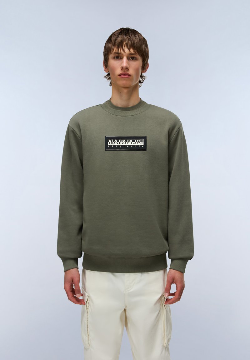 Olijfgroen sweatshirt met een ronde hals, lange mouwen en geribde manchetten. Heeft een zwart rechthoekig logo in het midden.