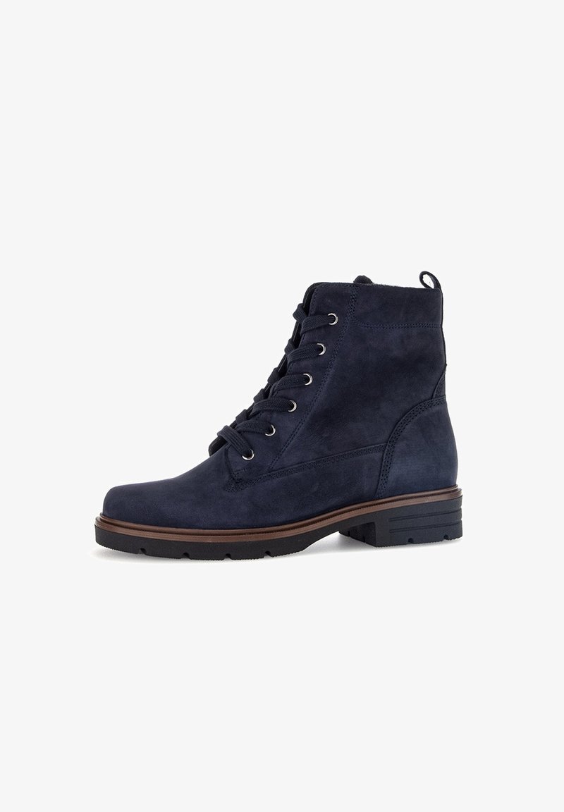 Bottine en daim bleu marine avec un bout rond, un système de laçage sur le devant et une semelle en caoutchouc texturée. Présente une couture apparente et une languette de tirage.