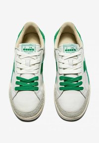Sneaker bianche con dettagli in suede verde e suole in gomma testurizzata. Due paia di lacci verdi, logo sulla linguetta, design classico da scarpa da tennis.