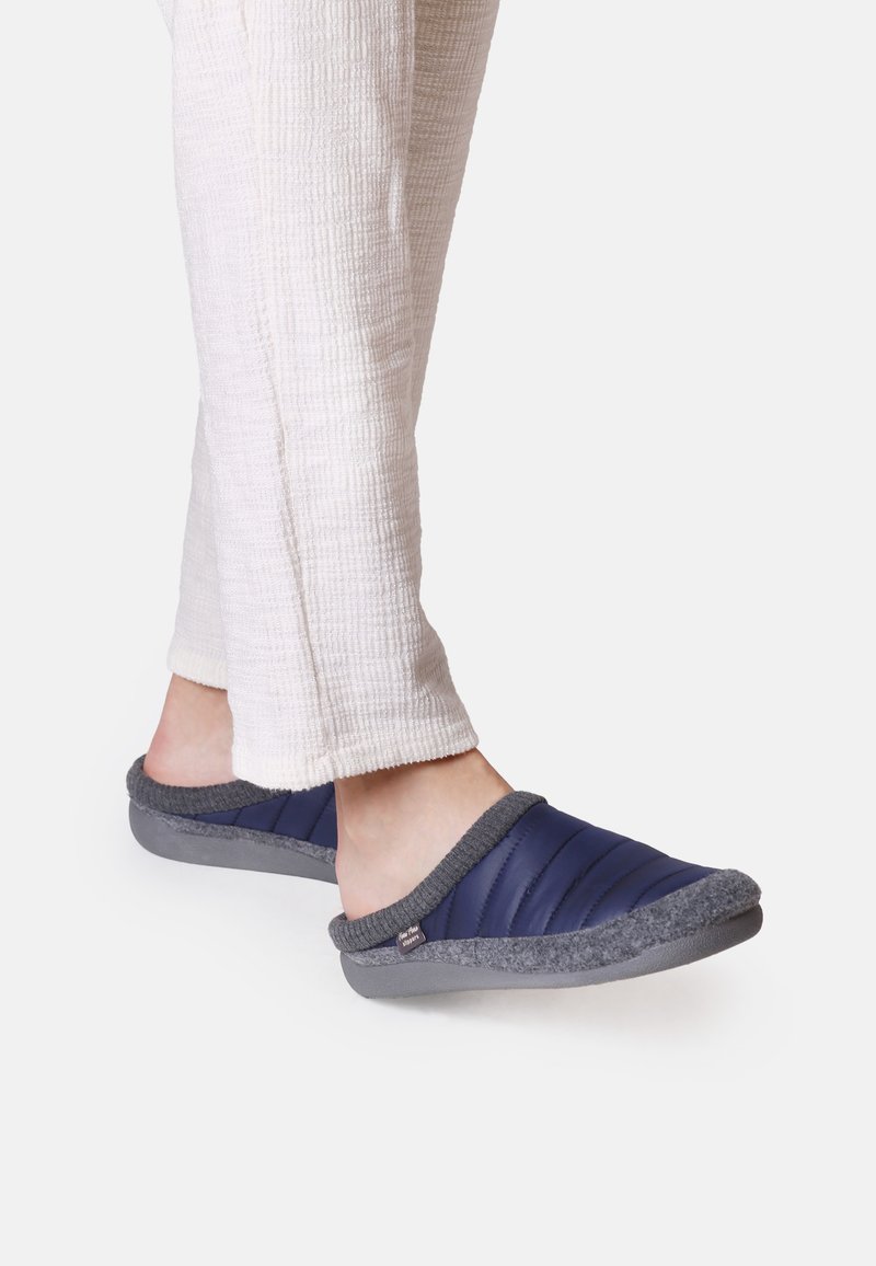 Pantofole slip-on imbottite di colore blu navy con accenti in feltro grigio e suola in gomma. Indossate con pantaloni chiari e strutturati.