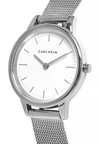 Reloj con correa de malla plateada, esfera blanca redonda, marcadores de hora plateados finos y movimiento de tres agujas. Nombre de la marca "C AR LHE IM" mostrado.