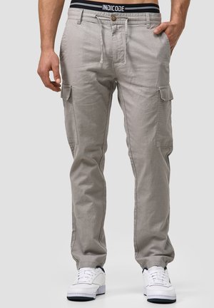 Light grey cargo pants with a drawstring waist, multiple side pockets, and stitching details. Paired with white sneakers.
