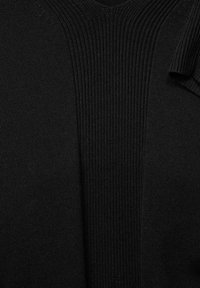 Czarny dzianinowy top z dekoltem w serek, z prążkowanym wzorem wzdłuż dekoltu i rękawów, prezentujący gładkie wykończenie i proste linie.