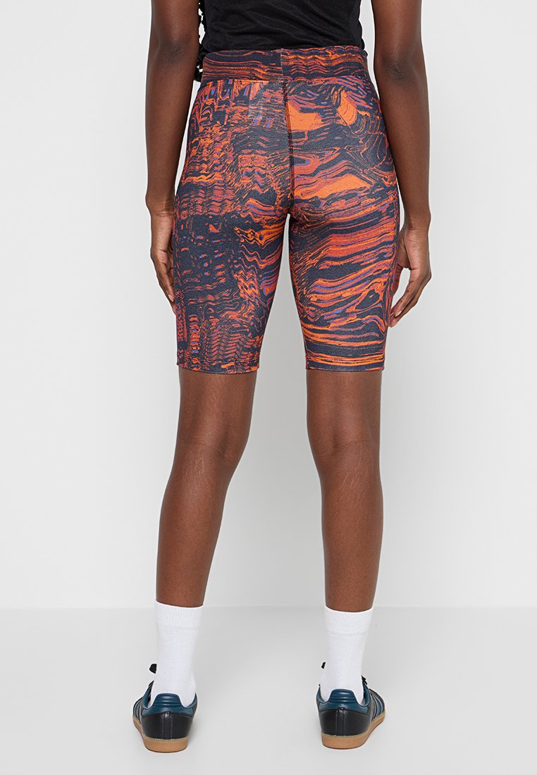 Pantalones cortos de ciclismo multicolores con un patrón en espiral en tonos naranjas, negros y rojos, hechos de una tela elástica y con una cinturilla de altura media.