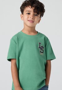Tricou verde din bumbac, cu mâneci scurte, decolteu rotund și un logo brodat "LS" și "Levi's" pe piept.