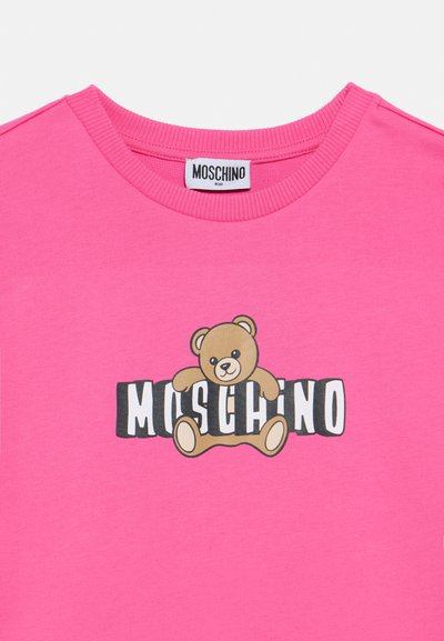 Ροζ βαμβακερό T-shirt με γραφική παράσταση αρκούδας και κείμενο «Moschino» από κάτω. Ο σχεδιασμός με στρογγυλή λαιμόκοψη έχει ριμπ λεπτομέρειες γύρω από το γιακά.