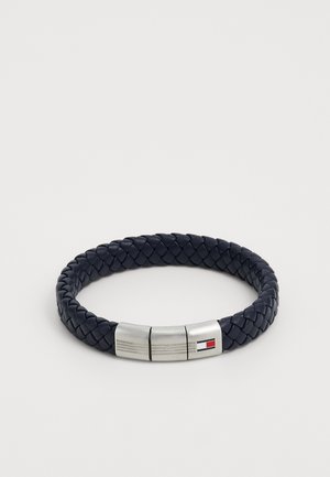 Navy blue braided leather bracelet with a silver magnetic clasp featuring a small rectangular red, white, and blue logo.