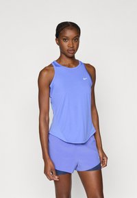 Αθλητικό τοπ και σορτς Nike σε ανοιχτό μωβ. Διαθέτει λείο ύφασμα, σχεδιασμό racerback και λογότυπο στο στήθος.