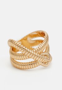 Bague en métal doré avec un design enroulé. Elle présente trois bandes entrelacées et un détail en nœud, exhibant une texture de surface lisse et brillante.