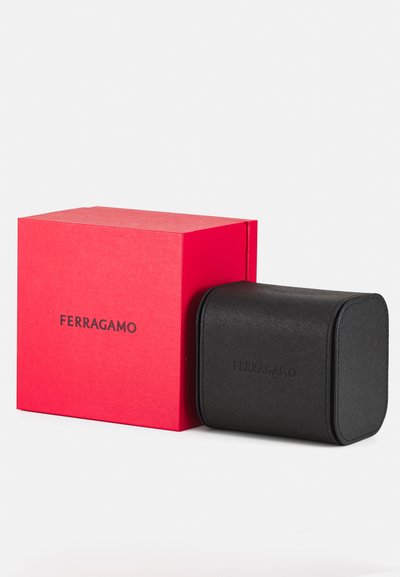 Black leather accessory case with a textured finish beside a red box featuring "FERRAGAMO" in black lettering, showcasing a simple, rectangular design.