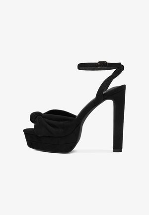 Czarne sandały na wysokim obcasie z węzłem, zamszowa cholewka, platforma oraz regulowany pasek na kostkę. Gładka faktura i wysoki obcas w stylu stiletto.