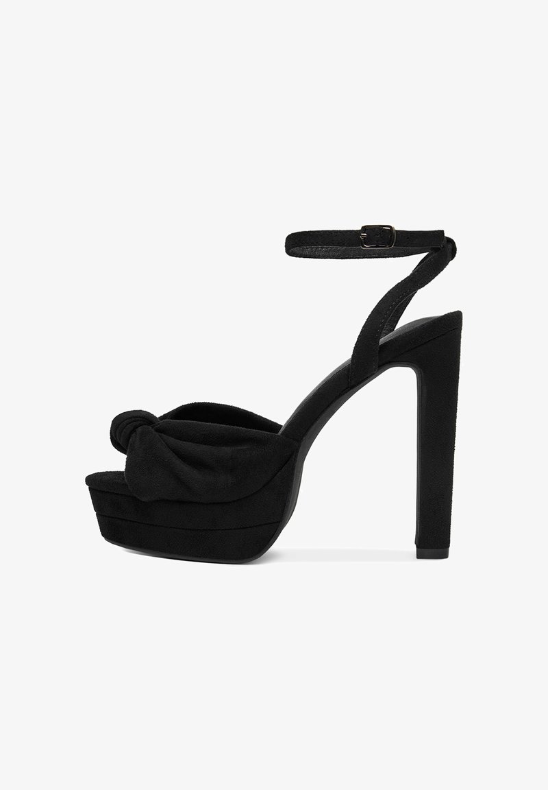 Černé vysoké sandály na podpatku s uzlovým svrškem z semiše, platformovou podrážkou a nastavitelným páskem kolem kotníku. Hladký povrch a vysoký jehlový podpatek.