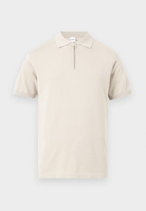 Beiges Poloshirt mit kurzen Ärmeln, umgelegtem Kragen und kurzem Frontreißverschluss vor einfarbigem Hintergrund.