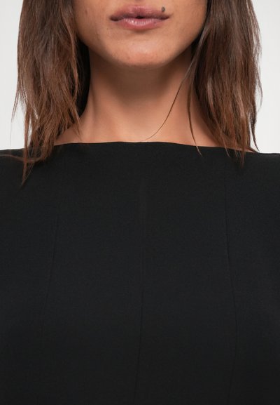 Black fitted garment with a wide neckline, smooth texture, and subtle seam detailing, displaying a sleek, minimalistic design.