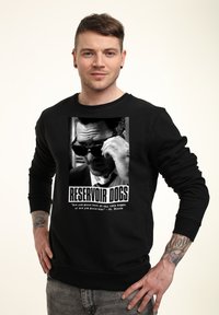 Felpa nera con una grafica stampata di un personaggio con occhiali da sole tratto da "Reservoir Dogs". Sotto c'è la scritta "RESERVOIR DOGS."