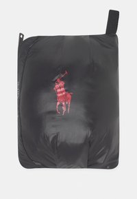 Černá prošívaná vesta s hladkou lesklou texturou, na jejímž středu je výrazné červené logo hráče polového póla. Součástí je horní poutko pro zavěšení.