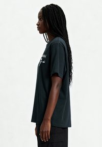 T-shirt en coton noir à manches courtes, avec un imprimé graphique sur le devant. Coupe décontractée, col rond et texture douce.