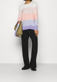 Knitted sweater with horizontal stripes in white, pink, and lavender, paired with black wide-leg pants and a green handbag.