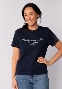 Dunkelblaues Baumwoll-T-Shirt mit weißem Text, der "früher war mehr Lametta" lautet. Kurze Ärmel, runder Ausschnitt und lässige Passform.