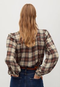 Tjekket skjorte med knapper i beige, brun og navy. Har pufærmer og en afslappet pasform. Bagerste visning viser skjorten stoppet ind i højtaljede jeans.