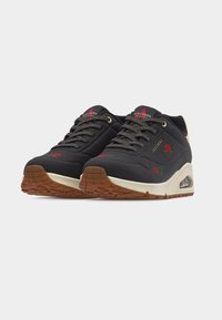 Baskets Skechers noires avec broderie de rose rouge, semelle intermédiaire blanche, semelle extérieure en caoutchouc marron et lacets noirs sur fond blanc.