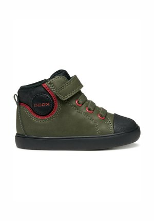 Groene hoge sneaker met zwarte rubberen neuskap, rode accenten, klittenbandsluiting en een gestructureerd stofdetail aan de zijkant.