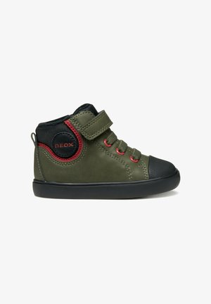 Sneaker verde alto con punta in gomma nera, dettagli rossi, strap in Velcro e trama di tessuto sulla parte laterale.