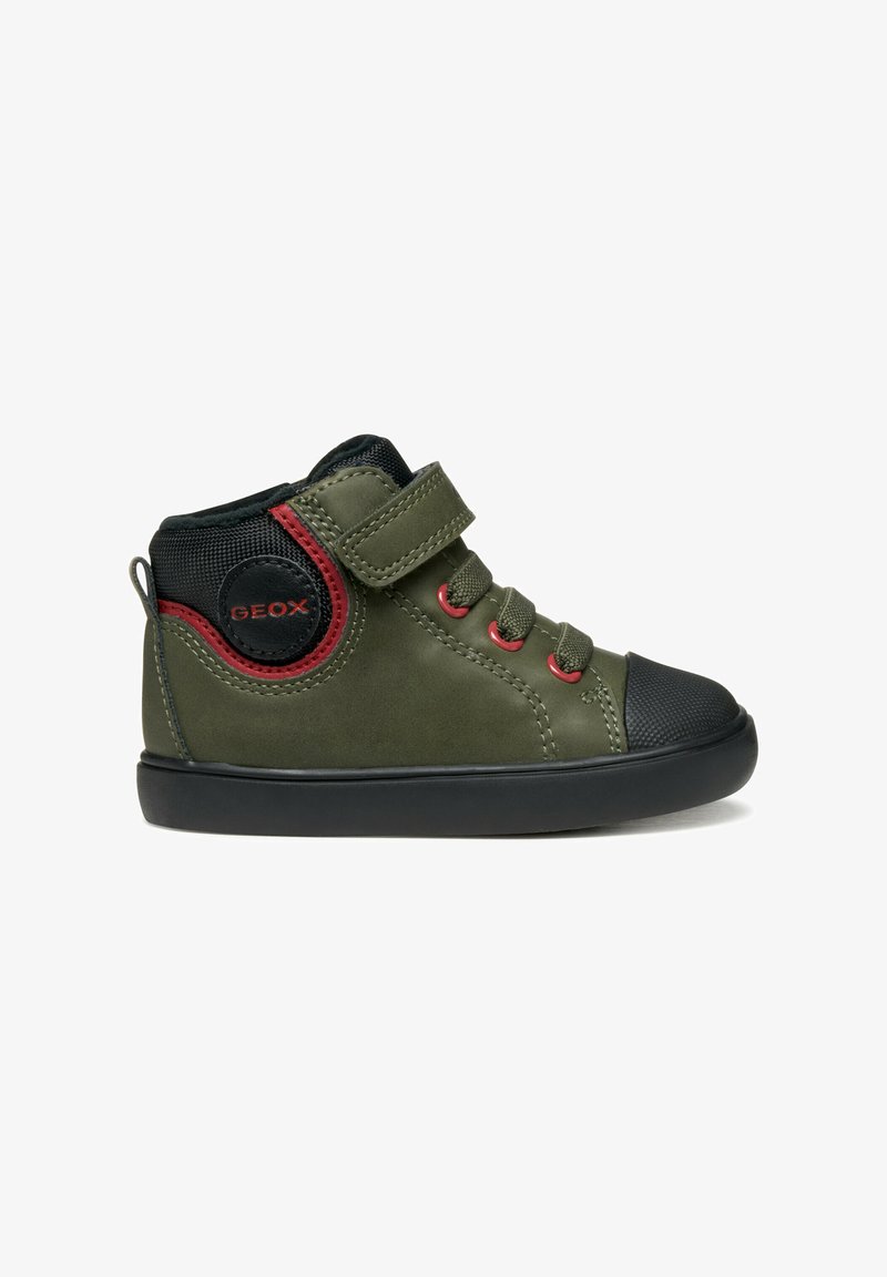 Zapatilla alta verde con punta de goma negra, acentos rojos, correa de velcro y detalle de tela texturizada en el lateral.