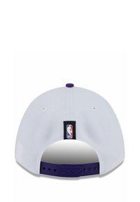 Weißes Baseballcap mit einem lila Akzent auf der Rückseite. Besitzt ein schwarzes NBA-Logo-Patch und einen Kunststoff-Snapback-Verschluss. Strukturierter Stoff.