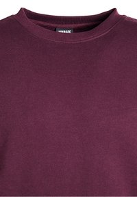 Primo piano di un maglione a maniche lunghe, girocollo, di colore viola scuro, con un'etichetta del brand visibile all'interno del colletto.