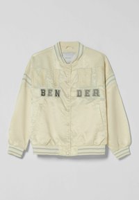 Kremowa satynowa kurtka bomberka z kontrastowymi niebieskimi i białymi paskami na ściągaczach oraz dolnej krawędzi. Posiada dużą haftowaną aplikację z przodu.