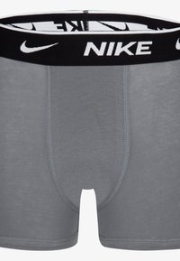 Grå bomuldsboxershorts med sort linning med hvidt "NIKE"-logo. Glat tekstur, tætsiddende design og kontrastsyede detaljer.