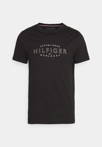 Camiseta de algodón negra con cuello redondo, mangas cortas y texto impreso en blanco que dice "ESTABLECIDO HILFIGER MCM LXXXV."
