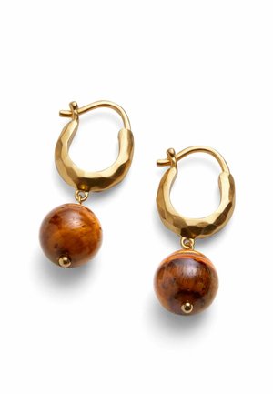 Pendientes de aro martillado tono dorado con colgantes de piedras redondas de ojo de tigre sobre un fondo blanco.