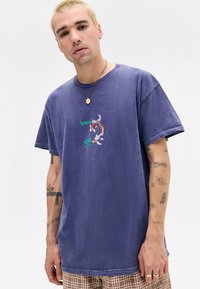 Modré bavlnené tričko s voľným strihom, krátkymi rukávmi a vyšívaným motívom kaprov koi s zeleným textom.