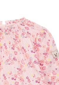Abito floreale rosa con scollatura arricciata, caratterizzato da gruppi di piccoli fiori gialli, viola e rosa. Include un dettaglio con una toppa a forma di orso.