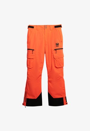 Pantalones de nieve de color naranja brillante con acentos negros, múltiples bolsillos tipo cargo, bolsillos con cremallera y puños reforzados para durabilidad y funcionalidad.