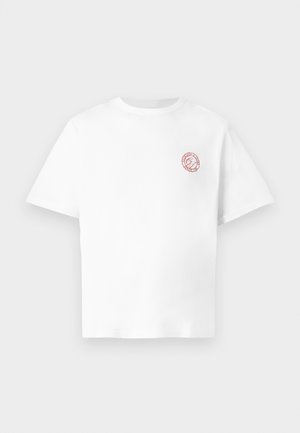 T-shirt de algodão branco com decote redondo, mangas curtas e um pequeno emblema gráfico vermelho no lado esquerdo do peito. Textura suave em todo o tecido.