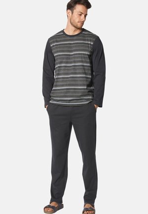 Long-sleeve shirt with a patterned gray and black body, and solid black sleeves paired with dark gray pants and sandals.