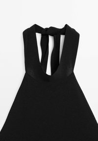 Top halter nero in tessuto a maglia testurizzato, con spalline larghe e chiusura a fiocco sul retro. Il design enfatizza una silhouette semplice.